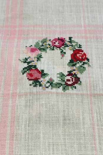 Nahansicht des gestickten Rosenkranzes auf dem rosa karierten Sajou Geschirrtuch in Ecru 